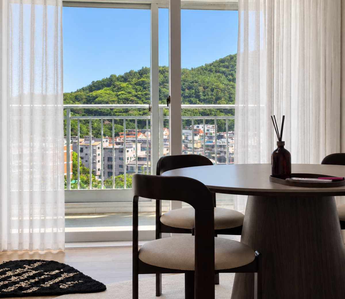커튼 너머로 산이 보이는 거실 다이닝 공간